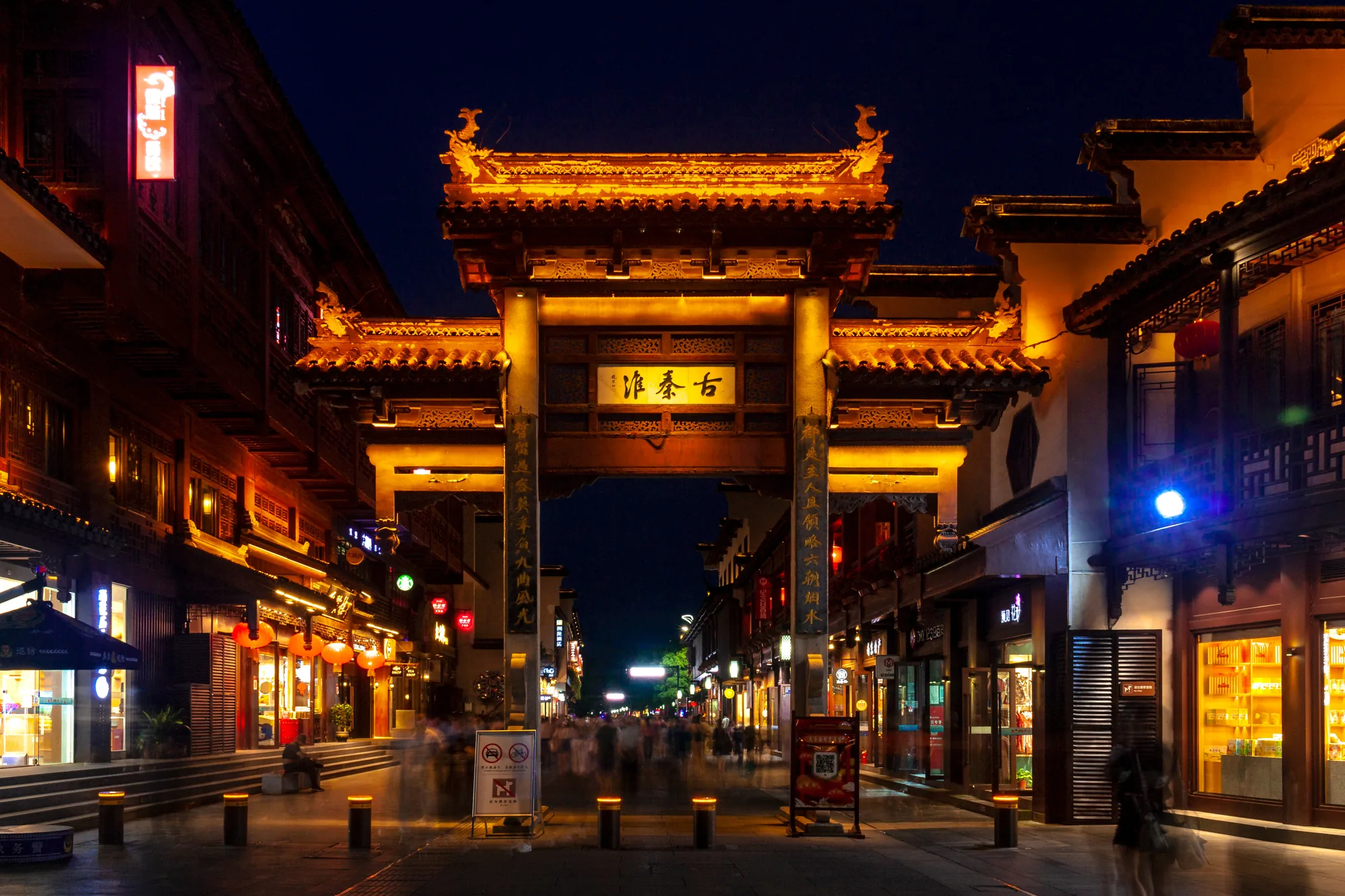 The illuminated Fuzimiao archway with shops and evening visitors in Nanjing
