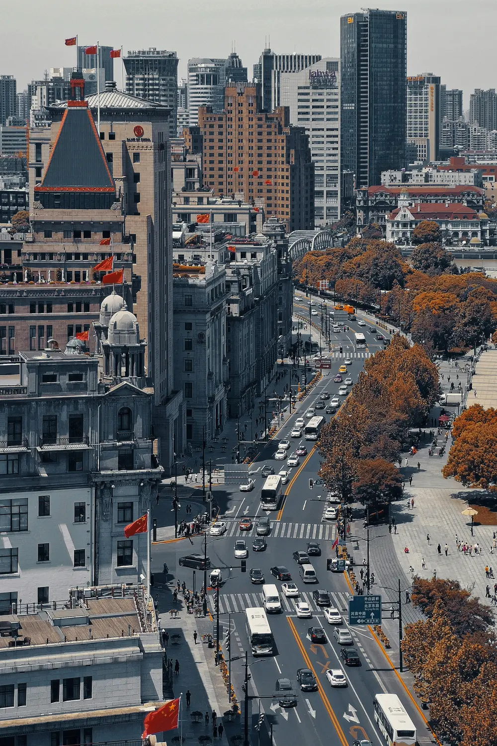 A central Shanghai avenue combining historic civic buildings, plane trees, traffic and modern towers